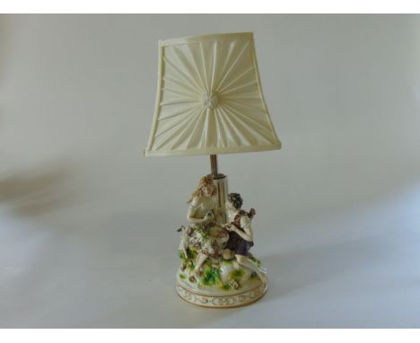 An early 20th century continental lamp base in the 18th century manner with applied figures of a goatherd and his female comp