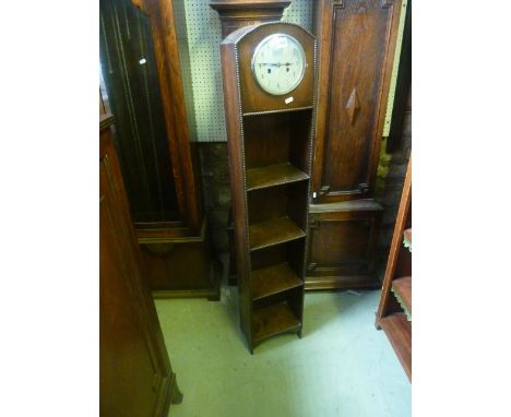 A small 1930s oak grandmother clock enclosing a 2-train movement, the trunk in the form of a 4-tier bookcase, 25cm wide