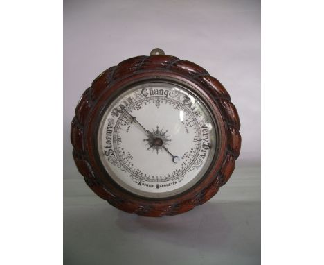 An Edwardian aneroid barometer, the oak case with rope twist borders and porcelain dial