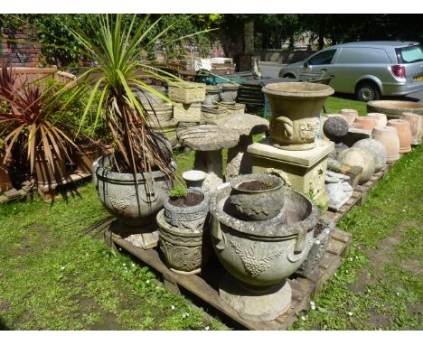 A pair of weathered cast composition stone garden urns of circular tapered form with raised relief ring handles and bunches o
