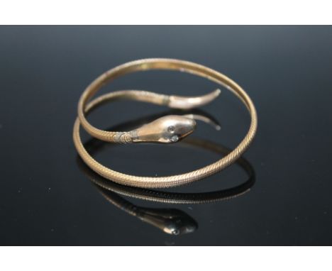 A 'SNAKE' BANGLE, set with two diamonds for eyes, stamped 9ct with sprung metal core