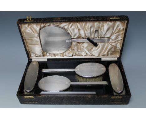 AN ART DECO HALLMARKED SILVER CASED SIX PIECE DRESSING TABLE SET BY WILLIAM NEALE LTD - BIRMINGHAM 1939, having typical engin