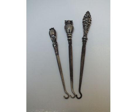THREE EARLY 20TH CENTURY SILVER HANDLED BUTTON HOOKS, to include an unusual owl example with Birmingham hallmarks