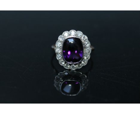 A LADIES 9CT AMETHYST AND DIAMOND RING, set with a central cabochon type dark amethyst measuring 11.3 mm x 8.9 mm totalling a