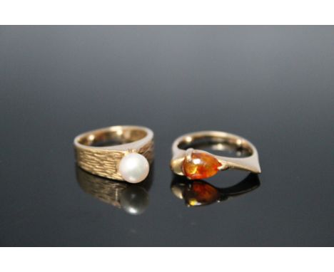 TWO GOLD DRESS RINGS, one set with a cultured pearl, ring size H 1/2, the other shaped ring set with a tear drop shaped amber