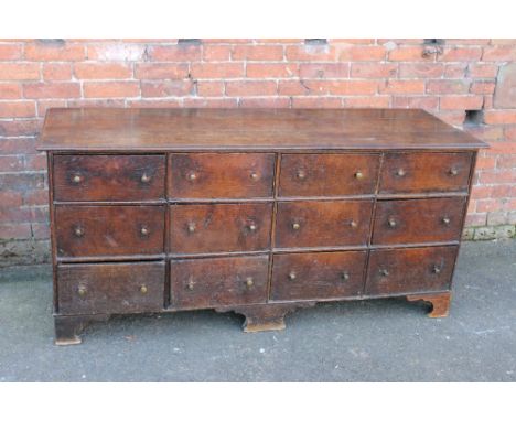 A 19TH CENTURY OAK COUNTRYMADE CHEST OF TWELVE DRAWERS, the typical three plank top above twelve short drawers, raised on sha