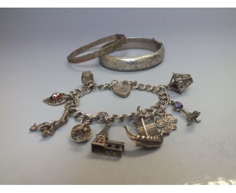 A HALLMARKED SILVER HINGED BANGLE, together with a smaller hallmarked silver bangle and a charm bracelet with attached charms