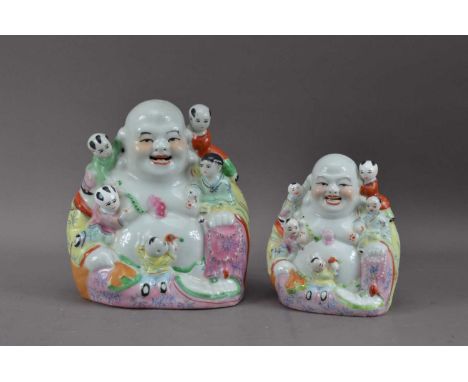 Two Chinese ceramic Buddha's with children, of differing sizes, 23cm & 17cm high (2)