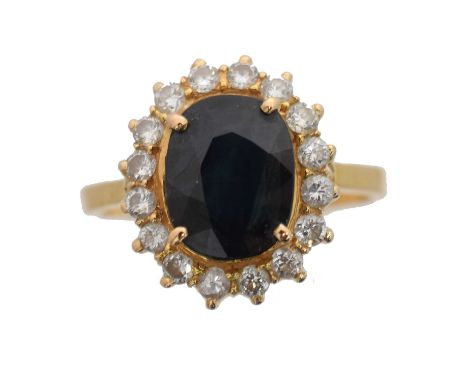 A sapphire and diamond cluster ring. The oval shape synthetic sapphire weighing approx. 2cts within a brilliant cut diamond s