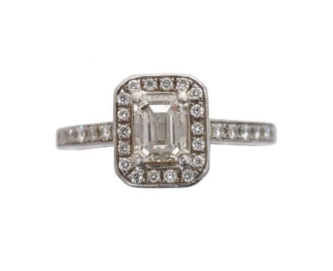 A platinum diamond cluster ring.  The emerald cut diamond weighing 0.70ct within a brilliant cut diamond halo surround and si