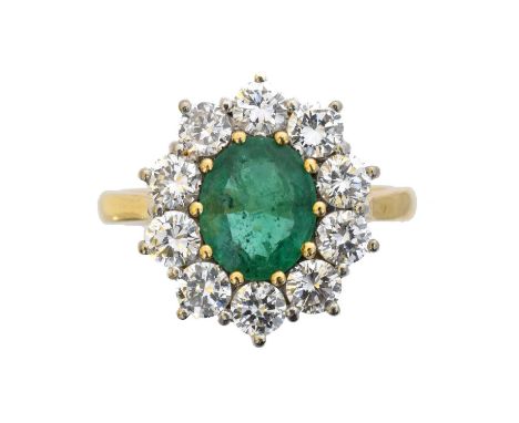 An 18ct gold emerald and diamond cluster ring. The oval shape emerald weighing approx. 1.15cts within a brilliant cut diamond