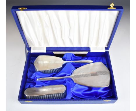 Cased modern hallmarked silver dressing table set comprising hand mirror, two brushes and comb, all with engine turned decora