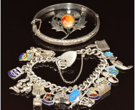 A silver charm bracelet with 20 charms including enamel shields, pixie, Eiffel Tower, etc, silver bangle (74g) and thistle br