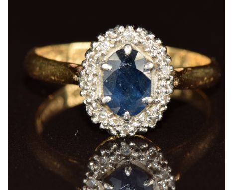 An 18ct gold ring set with an oval cut sapphire surrounded by diamonds in a platinum setting, 3.3g, size N