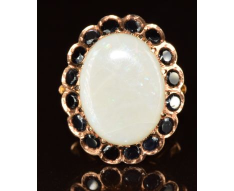 A 14k rose gold ring set with an oval cut opal cabochon surrounded by round cut sapphires, 8.4g, size M