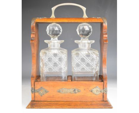 19th or early 20thC oak tantalus with metal fretwork mounts and two cut glass decanters, H33cm