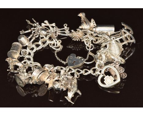 A silver charm bracelet with twenty charms including keys, Links of London '2000' in a heart, horses, woodpecker, etc , 70.1g