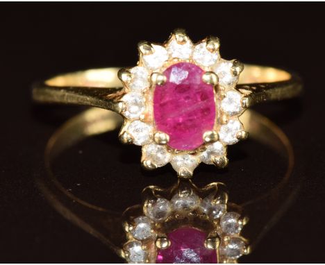 A 14k gold ring set with an oval cut ruby surrounded by diamonds, 2.6g, size K