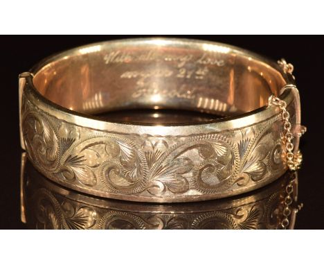 A 9ct gold bangle with engraved scrolling decoration, 49.9g, 5.8 x 5.2cm