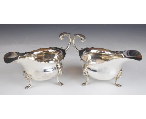 Pair of George V hallmarked silver sauce boats with shaped edges and scroll handles, raised on three lion mask and paw feet, 