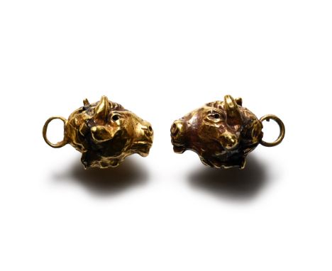 7th century B.C. Matched pair of hollow-formed pendants, each a bull's head modelled in the round with a rosette to the rear 
