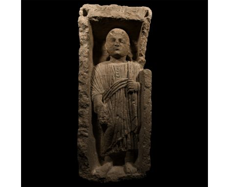 3rd-4th century A.D. Modelled in the half-round as a man standing on an integral plinth, round face with short curly hair, wi