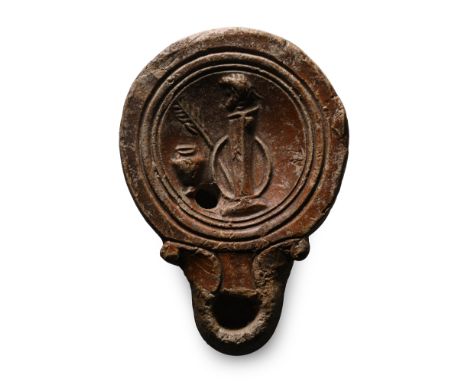 2nd century A.D. Short nozzle with volute scrolls, low discus with concentric circles, central motif of a male bust atop a co