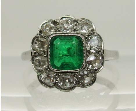 An 18ct white gold and platinum emerald and diamond ring the central cushion cut emerald is approx 6mm x 5.7mm, surrounded wi