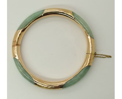 A 14ct gold hinged bangle set with Chinese green hardstone stamped both 583 and 14k, inner diameter 5.8cm, weight 22.8gms