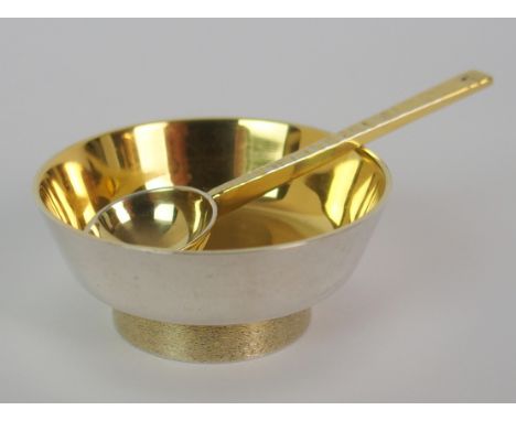 A silver gilt salt by Stuart Devlin, London 1970, of circular shape on textured plinth base with server, 4cm diameter