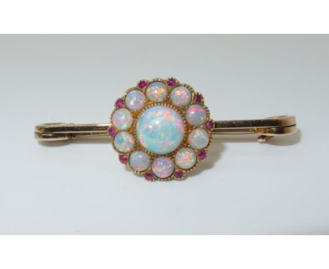 A bright yellow metal opal and ruby flower cluster brooch hallmark indistinct, opals are very colourful.  Stone set area 1.6c