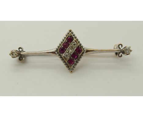 A yellow and white metal diamond and ruby brooch with central diamond gemstone set panel with the bar terminating in two old 