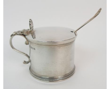 A silver mustard pot maker's marks J M Limited, London 1907 of cylindrical shape with gadrooned border, scrolling handle with
