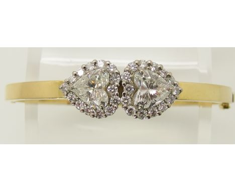 An 18ct yellow and white gold twin hear shaped diamond bangle designed and made by Eric Smith. The two heart shaped diamonds 