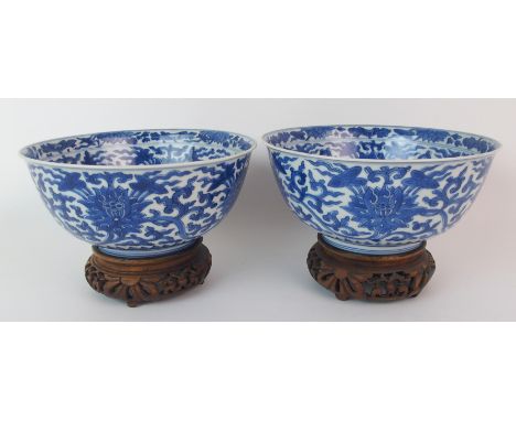 A pair of Chinese blue and white bowls painted with lotus and scrolling foliage, within double line bands, bears Kangxi six-c