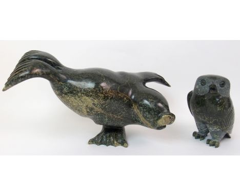 An Inuit hardstone carving of a seal balancing on one flipper, 24cm high x 36cm wide and a carving of an owl, 18cm high (2) P
