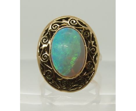 An opal ring with a pierced scrolled yellow metal mount the white opal has good colour play, ring is hallmarked but it is unr