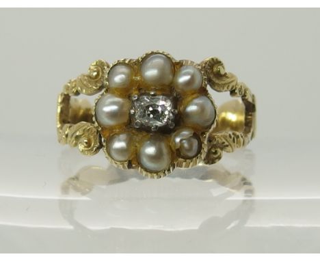 A Victorian mourning ring with scrolled foliate yellow metal mount, set with a natural pearl set flower with a central cushio