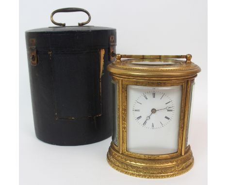 A late 19th Century brass oval striking carriage clock the enamel dial with Roman numerals, twin barrel movement and shaped h