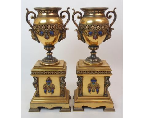 A pair of late 19th/early 20th Century garnitures of classical urn shape with champleve enamel decoration, upon squared bases