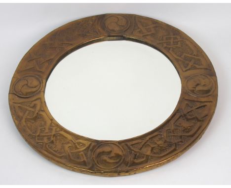 A Glasgow Schools Arts and Crafts brass framed mirror of circular form, the frame with repousse Celtic knotwork decoration an
