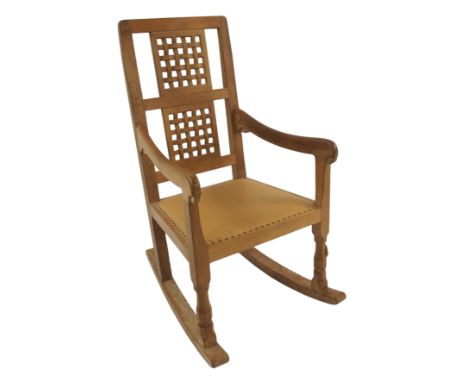 A Robert 'Mouseman' Thompson oak rocking chair the open lattice panelled back joined with scroll arms above a leather studded