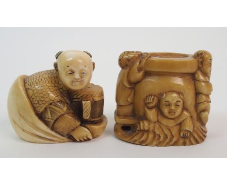 A Japanese ivory netsuke of Daikoku signed, 4cm wide and a netsuke of a cauldron with three figures, signed, 3.5cm high (2)