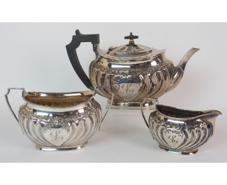 An Edwardian three piece silver tea service by Atkin Brothers, Sheffield 1901, of oval form with floral embossed borders and 