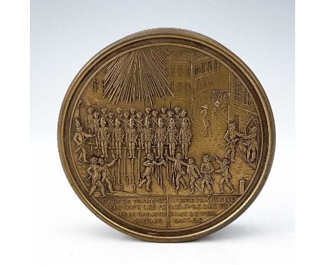 A nineteenth-century French metal and bois durci snuff box, of circular form with the cast cover, depicting a scene of guards
