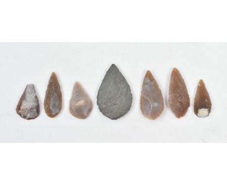 A collection of seven Neolithic Stone Age flint carved arrowheads. Each arrowhead of differing proportions, one of stone; one