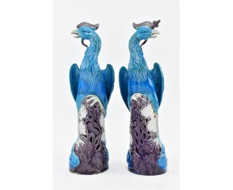 A pair of Chinese porcelain turquoise and aubergine glazed phoenixes. Each moulded in mirror image of a mythical bird perched