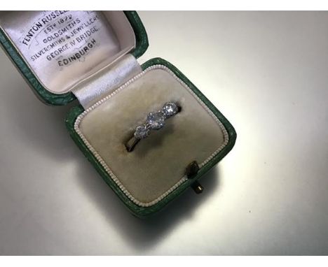 An early 20th century three stone diamond ring, the graduated round brilliant-cut stones claw set on an 18ct white gold and p