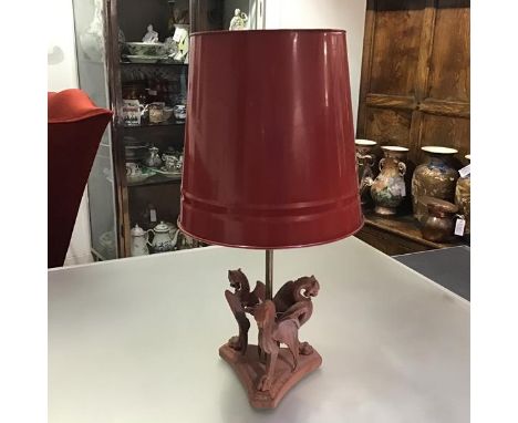 A painted cast-iron table lamp modelled as three griffins on a triform platform base issuing a brass rod lamp fitting. Height