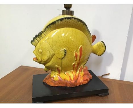 A 1950's novelty table lamp, modelled as a tropical fish amidst coral, in a yellow crackle glaze, mounted on an ebonised wood